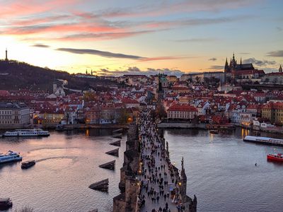  Vivid Sunset at Charles Bridge: Experience the magic of a vivid sunset at the historic Charles Bridge in Prague. As the sun dips below the horizon, the bridge comes alive with the movement of people, their silhouettes adding to the enchanting atmosphere. The warm, golden lights along the bridge and the city's skyline create a stunning contrast against the deepening twilight. This picturesque scene captures the timeless beauty and romantic allure of Prague, making it an unforgettable moment for all who visit