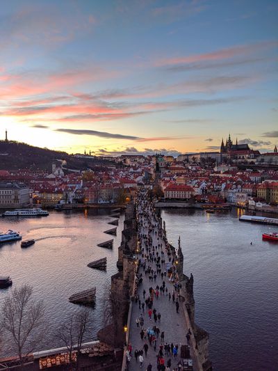  Vivid Sunset at Charles Bridge: Experience the magic of a vivid sunset at the historic Charles Bridge in Prague. As the sun dips below the horizon, the bridge comes alive with the movement of people, their silhouettes adding to the enchanting atmosphere. The warm, golden lights along the bridge and the city's skyline create a stunning contrast against the deepening twilight. This picturesque scene captures the timeless beauty and romantic allure of Prague, making it an unforgettable moment for all who visit