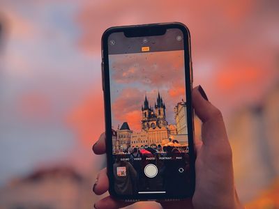  Capturing the Beauty of Old Town Square in the Rain: A mesmerizing view of Prague's Old Town Square at sunset, as seen through the lens of an iPhone camera held by a female hand. Raindrops create a captivating visual effect, enhancing the charm of this historic square. The soft, colorful hues of the sunset contrast beautifully with the rain-slicked cobblestones. This unique perspective captures the essence of Prague's romantic allure even in wet weather.